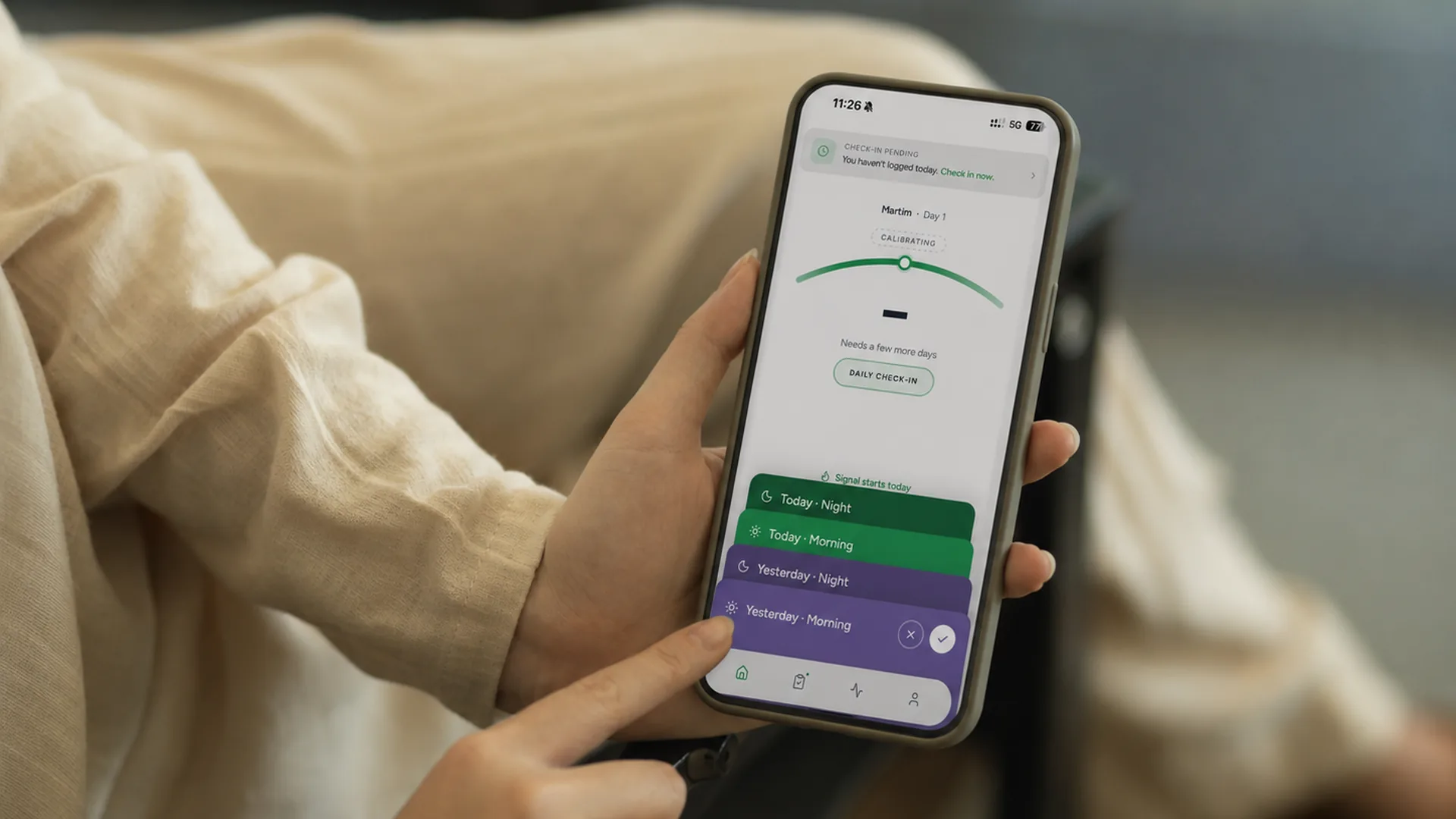 Hands holding a phone with the Tyttra app calibrating a BioScore from daily check-ins